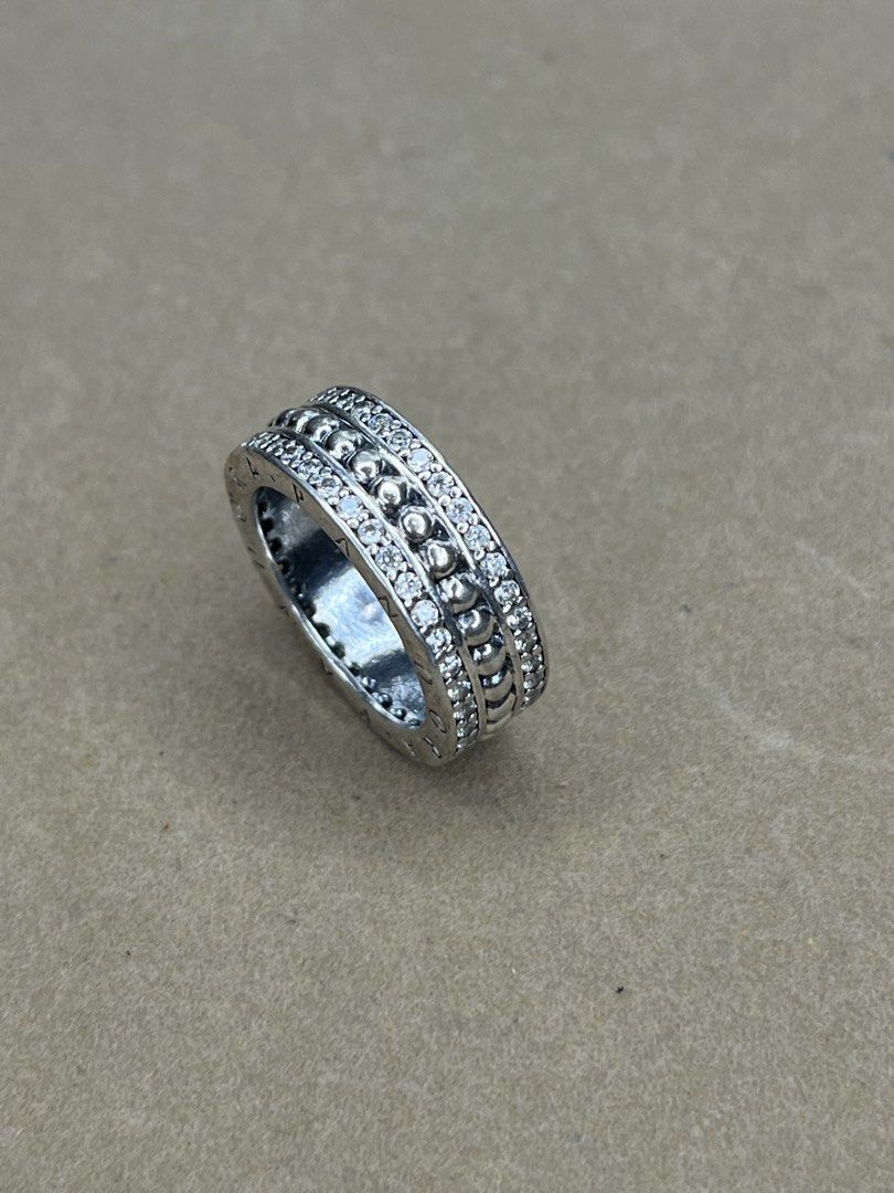 Pandora Pavé & Beaded Multi-Row Ring (Category: Rings) located in Bulacan. Submitted by vintagetreasureby.mivida (Listing ID 1467641103, Image 3). Description: - Brand: Pandora - Design: Wide band with three rows (raised beaded center, flanked by pavé crystals) - Details: Signature Pandora lettering engraved all around the outer edges - Finish: Silver-tone - Feel: Substantial weight, fits nicely with great sparkle - Condition: Minor everyday wear
