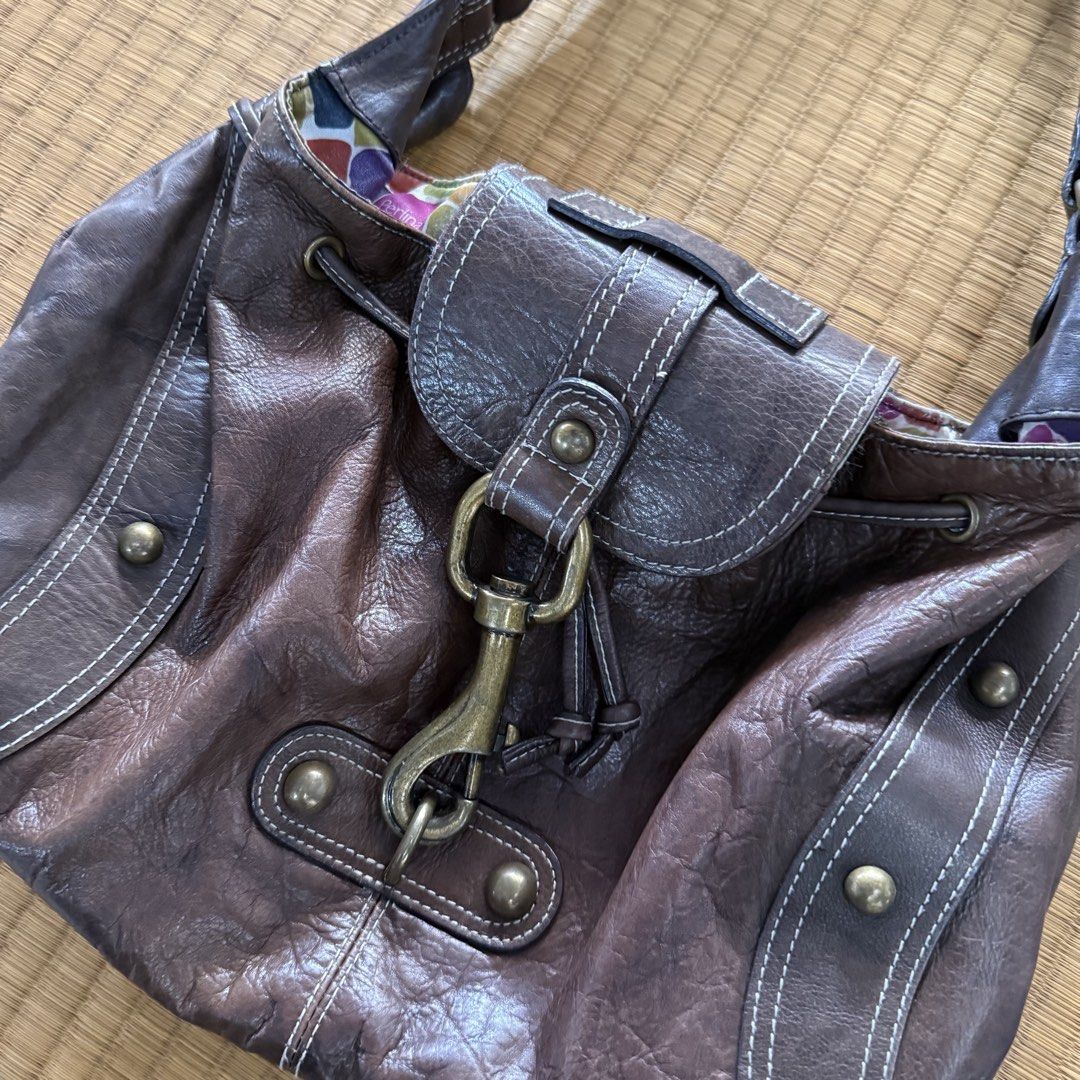 Perlina Studio Brown Leather Shoulder Bag with Colorful Lining (Category: Shoulder Bags) located in Manila. Submitted by preciousma24494 (Listing ID 1467674677, Image 1). Description: Brown leather handbag by Perlina Studio. Slouchy hobo style with contrast white stitching and brass-tone hardware. Front flap closure secured with a metal lobster clasp. Drawstring detail around the top edge. Inside has a colorful mosaic block pattern fabric lining 