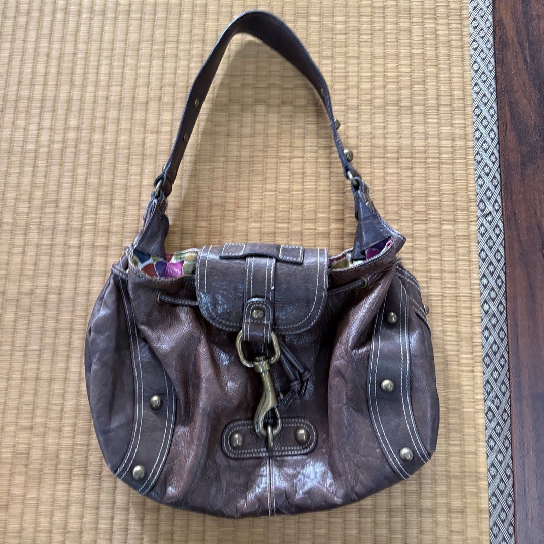 Perlina Studio Brown Leather Shoulder Bag with Colorful Lining (Category: Shoulder Bags) located in Manila. Submitted by preciousma24494 (Listing ID 1467674677, Image 2). Description: Brown leather handbag by Perlina Studio. Slouchy hobo style with contrast white stitching and brass-tone hardware. Front flap closure secured with a metal lobster clasp. Drawstring detail around the top edge. Inside has a colorful mosaic block pattern fabric lining 