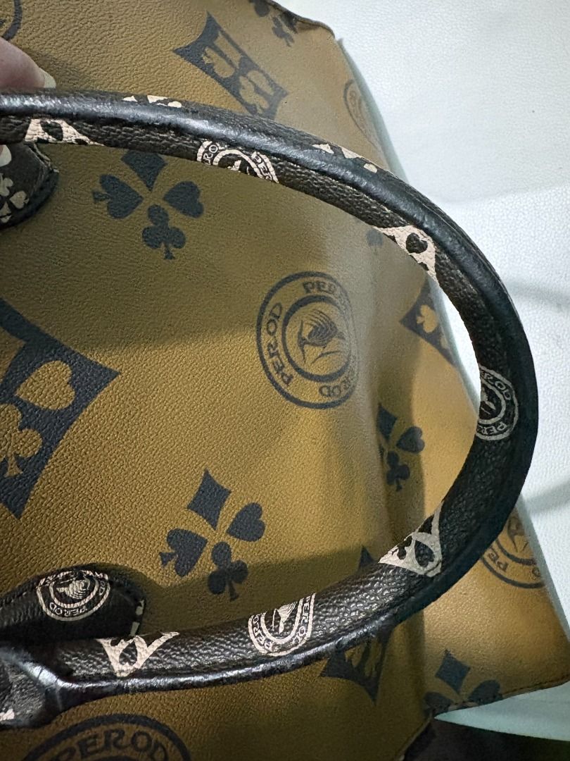 Perod Tote Bag with Card Suit Pattern (Category: Tote Bags) located in Paranaque City. Submitted by realjbe (Listing ID 1467612319, Image 3). Description: - Brand: Perod - Color: Olive green and mustard yellow with all-over card suit print (spades, clubs, diamonds) - Straps: Dual shoulder straps with matching print - Interior: Brown fabric lining with a zipped pocket and brand patch - Capacity: Roomy everyday carryall that fits all daily essentia