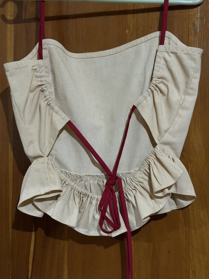 Pilya Beige Crop Top with Red Straps (Category: Sleeveless) located in Caloocan City. Submitted by sisi_p (Listing ID 1467655724, Image 2). Description: - Brand: Pilya - Size: XS - Color: Beige with deep red spaghetti straps - Design: Ruffled hem at bottom and back, open-back with tie closure.