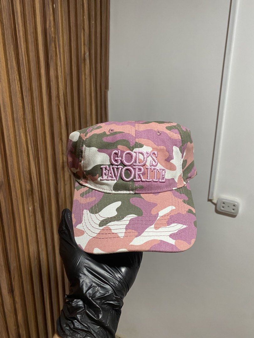 Pink Camo God's Favorite Baseball Cap (Category: Caps & Hats) located in Caloocan City. Submitted by heatedcaps4425 (Listing ID 1467802034, Image 1). Description: Pink camouflage baseball cap with embroidered lettering across the front reading God's Favorite. Adjustable strapback closure in the back. Interior shows 100 percent cotton tag and clean white sweatband lining. Unstructured low profile fit. Great streetwear accessory..