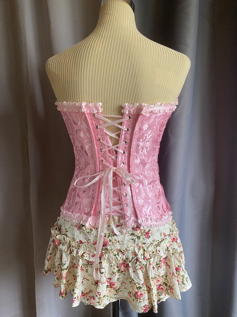 Pink Lace Up Corset Top (Category: Sleeveless) located in Cagayan de Oro. Submitted by curated_closetph (Listing ID 1467764348, Image 3). Description: — Size : M - L — Color: Pink — Textured brocade fabric with subtle floral satin patterns — Strapless sweetheart neckline accented with a ruffled lace trim — Front busk closure with silver metal hooks for easy wear — Traditional adjustable ribbon lace-up back to tighten or loosen the fit — Full stru