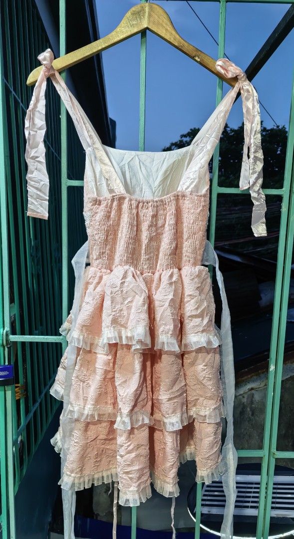 Pink Ruffle Mini Dress with Bow Straps (Category: Dresses) located in Quezon. Submitted by miksxthrift (Listing ID 1467736719, Image 2). Description: - Pink mini dress with textured fabric and layered ruffles - Satin shoulder straps that tie into bows - White lace trim on the chest with faux pearl buttons - Smocked back panel for a comfortable and stretchy fit - Includes side ties for adjustable styling.