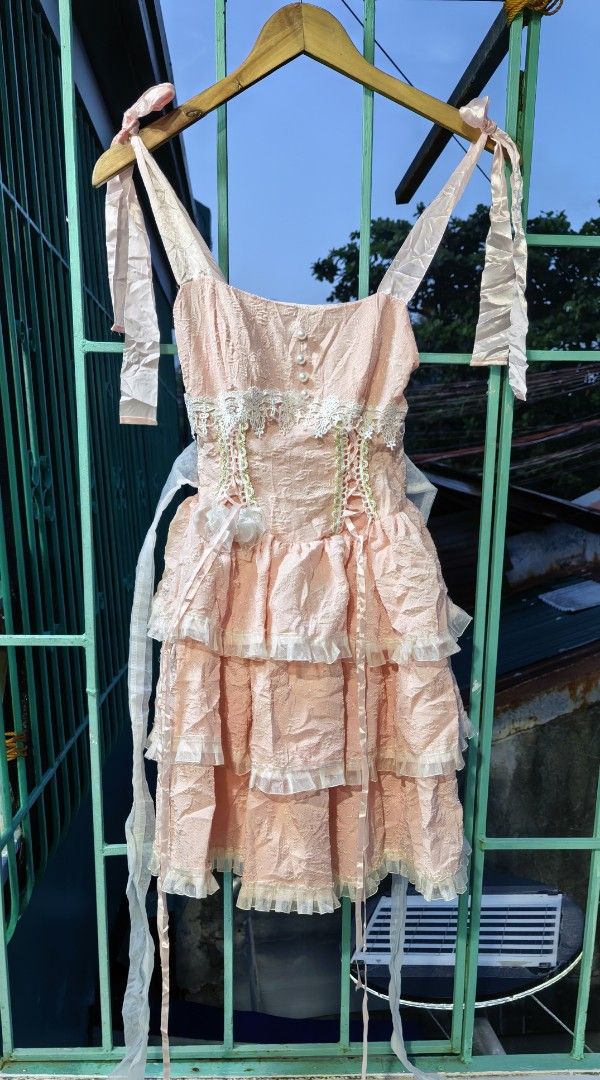 Pink Ruffle Mini Dress with Bow Straps (Category: Dresses) located in Quezon. Submitted by miksxthrift (Listing ID 1467736719, Image 1). Description: - Pink mini dress with textured fabric and layered ruffles - Satin shoulder straps that tie into bows - White lace trim on the chest with faux pearl buttons - Smocked back panel for a comfortable and stretchy fit - Includes side ties for adjustable styling.