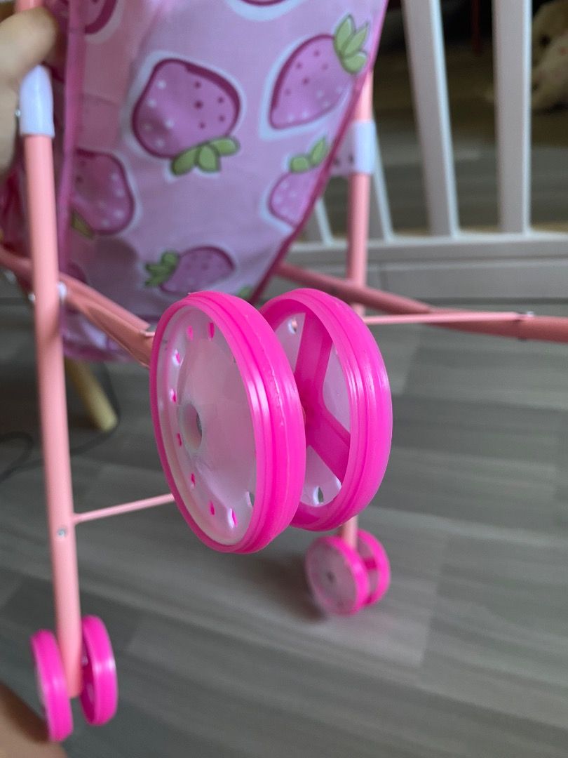 Pink Strawberry Print Doll Stroller (Category: Strollers) located in Bauang. Submitted by tinyhandspreloved (Listing ID 1467616017, Image 2). Description: - Adorable pink strawberry pattern fabric - Adjustable canopy that folds down or pulls up - Sturdy pink-painted metal frame with double wheels on each corner - Folds up compactly for easy storage - Lightweight design perfect for kids and their dolls -with minor flaw.