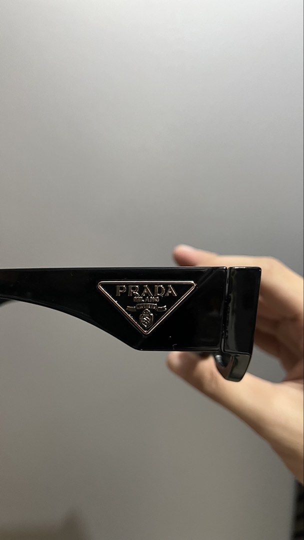 Prada Black Rectangular Sunglasses (Category: Sunglasses & Eyewear) located in Manila. Submitted by _jeanno (Listing ID 1467658395, Image 2). Description: - Brand: Prada - Color: Black with dark tinted lenses - Frame: Thick rectangular, modern minimalist style - Details: Signature gold triangular logo plaque on temple arms - Condition: Clean shape, ready to wear.