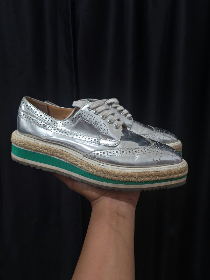 Prada Silver Metallic Brogue Platform Shoes Size 37 (Category: Loafers) located in Baguio. Submitted by solo_ukay (Listing ID 1467788728, Image 1). Description: - Brand: Prada - Style: Silver metallic leather brogues with wingtip perforations - Size: 37 (stamped inside) - Sole: Chunky platform with a stylish green stripe and woven jute detail - Branding: Gold Prada logo on insoles and debossed on rubber outsoles - Condition: Good pre-loved condit