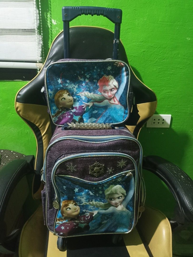 Preloved Frozen Roller Backpack and Lunch Bag Set (Category: Backpacks) located in Tarlac. Submitted by allinoneshop2178 (Listing ID 1467726279, Image 1). Description: - Official Frozen design featuring Anna and Elsa on purple denim-look fabric - Complete 2-in-1 set: rolling school bag and matching lunch bag - Lunch bag conveniently attaches to the main trolley handle - Smooth-rolling durable wheels with a sturdy telescopic handle - Spacious zipp