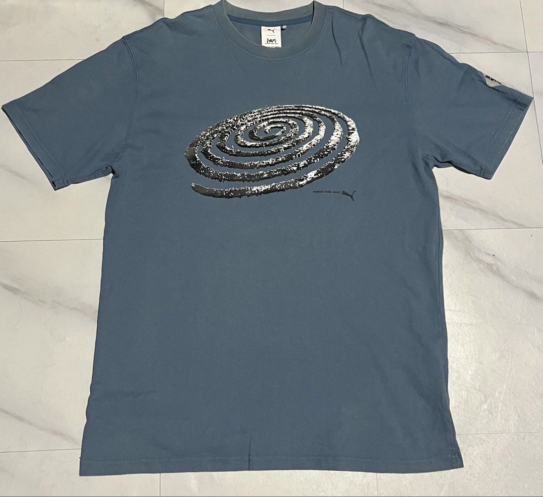 Puma x PAM Perks and Mini Graphic Tee (Category: Shirts) located in Cavite. Submitted by christianzuuu (Listing ID 1467662598, Image 2). Description: - Brand: Puma x P.A.M. (Perks and Mini) Collaboration - Color: Blue - Material: Soft, comfortable cotton - Design: Large spiral graphic print on front and back, with official collaboration patch on the sleeve - Size/Measurements: Chest width 21 inches, Length 28.5 inches - Mode of Payment: GCash, BP