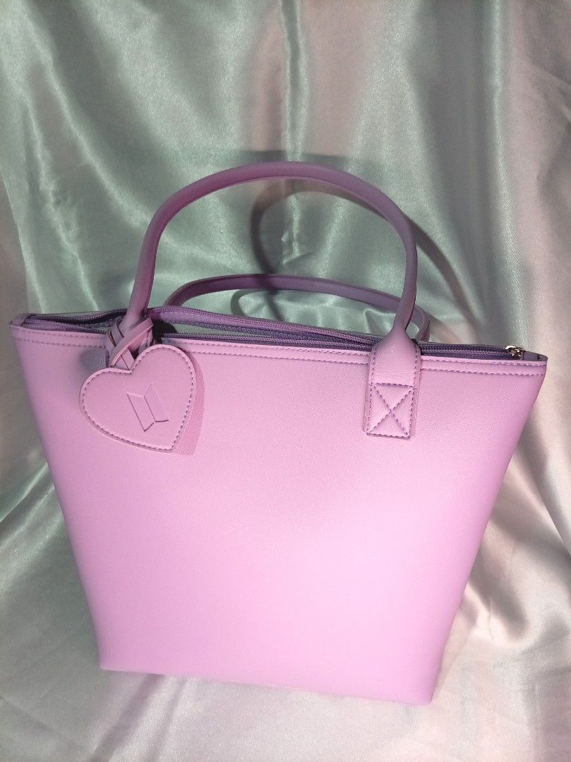 Purple BTS Heart Accent Tote Bag (Category: Tote Bags) located in Manila. Submitted by btsinpurple (Listing ID 1467691716, Image 1). Description: - Color: Light purple - Material: Smooth synthetic leather - Closure: Top zipper with matching pull - Inclusion: Heart-shaped BTS logo bag charm - Features: Twin carry handles and clean solid interior lining - Capacity: Roomy size perfect for daily essentials - Quality: Neat stitching along all seams an