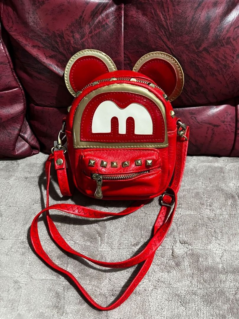 Red Mickey Mouse themed mini backpack crossbody bag (Category: Sling Bags) located in Caloocan City. Submitted by tinlala0116 (Listing ID 1467836582, Image 1). Description: - Color: Vibrant red with white logo detail on the front flap - Design: Fun mouse ears on top with trendy gold hardware and stud accents - Storage: Secure zipper closure with a handy front pocket - Comfort: Features an adjustable red strap for a customized fit - Style: Compact