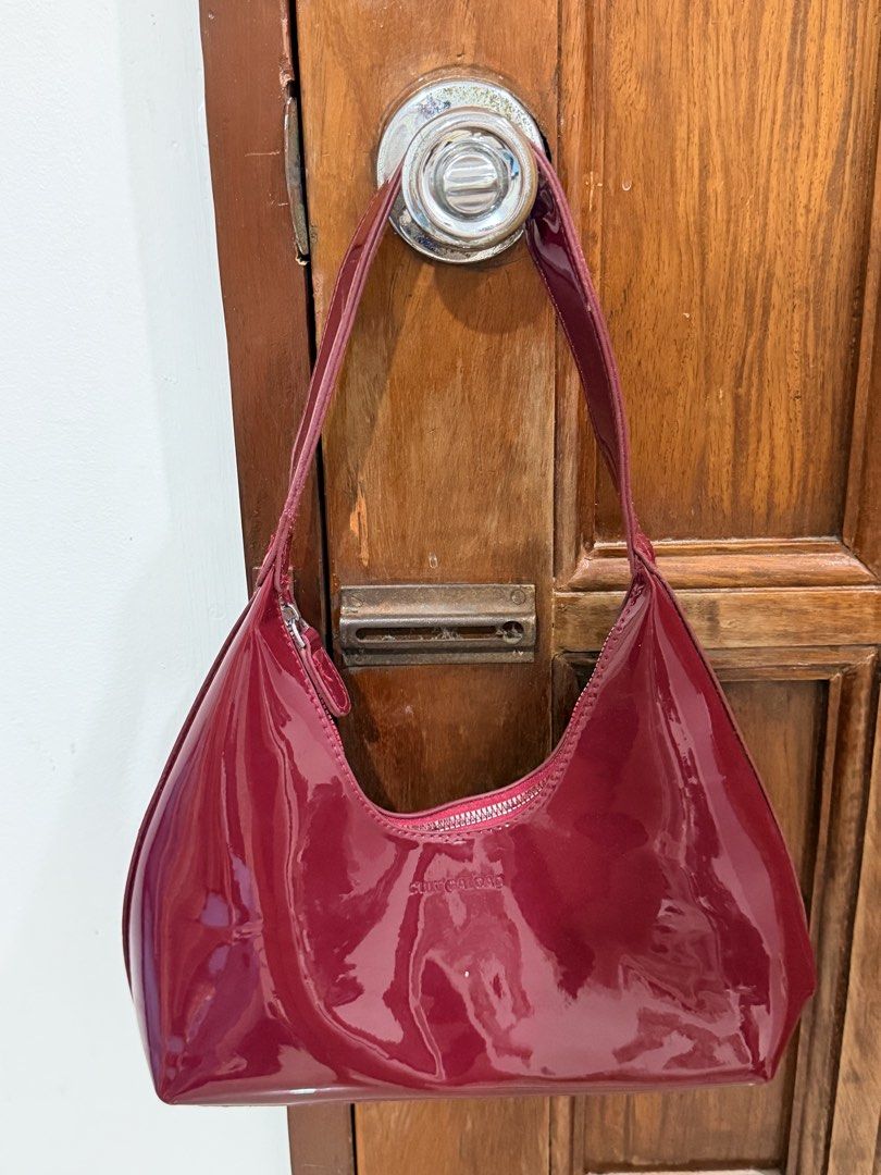Red Patent Leather Shoulder Bag (Category: Shoulder Bags) located in Kalibo. Submitted by goodfinds.club (Listing ID 1467766013, Image 1). Description: - Color: Deep red with a striking glossy finish - Material: Premium patent leather with smooth curves - Closure: Secure zippered top with matching zipper pull - Strap: Comfortable short shoulder strap attached on both sides - Branding: Subtle embossed lettering near the top center - Style: Clean, 