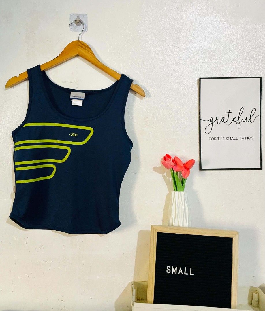 Reebok Tank Top (Category: Sleeveless) located in San Mateo. Submitted by safeearth21 (Listing ID 1467795557, Image 1). Description: - Brand: Reebok - Color: Navy blue with bright green graphic lines and logo - Size: Small (tagged at collar) - Neckline: Scoop neck - Material: Breathable athletic fabric - Condition: Great piece for workouts or casual streetwear.
