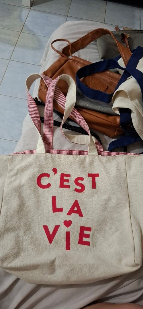 Reversible canvas tote bag (Category: Tote Bags) located in Paranaque City. Submitted by finders_thriftersph (Listing ID 1467737333, Image 1). Description: - Color: Cream with red typography and heart detail - Quote: "C'est La Vie" - Straps: Dual cream top handles + double striped red and white shoulder straps - Interior: Red and white striped lining - Size: Roomy everyday carryall - Perfect for: Groceries, books, school, work, or daily essential