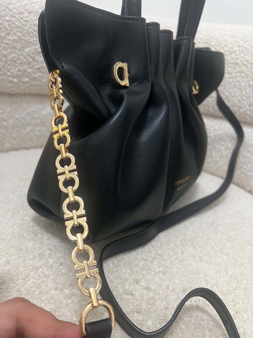 Salvatore Ferragamo Black Leather Shoulder Bag (Category: Luxury Bags & Wallets) located in Abulug. Submitted by jamiecammie (Listing ID 1467645376, Image 3). Description: Black leather shoulder bag by Salvatore Ferragamo. Made in Italy. Soft, pleated design with gold-tone hardware details. Includes dual top handles, an adjustable leather crossbody strap, and a decorative Gancini chain link strap. Stamped gold Ferragamo logo on the front. Clean i