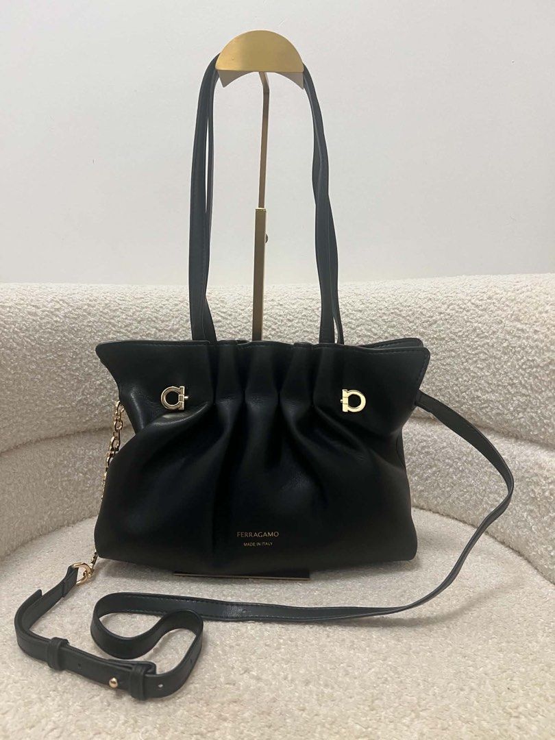Salvatore Ferragamo Black Leather Shoulder Bag (Category: Luxury Bags & Wallets) located in Abulug. Submitted by jamiecammie (Listing ID 1467645376, Image 2). Description: Black leather shoulder bag by Salvatore Ferragamo. Made in Italy. Soft, pleated design with gold-tone hardware details. Includes dual top handles, an adjustable leather crossbody strap, and a decorative Gancini chain link strap. Stamped gold Ferragamo logo on the front. Clean i