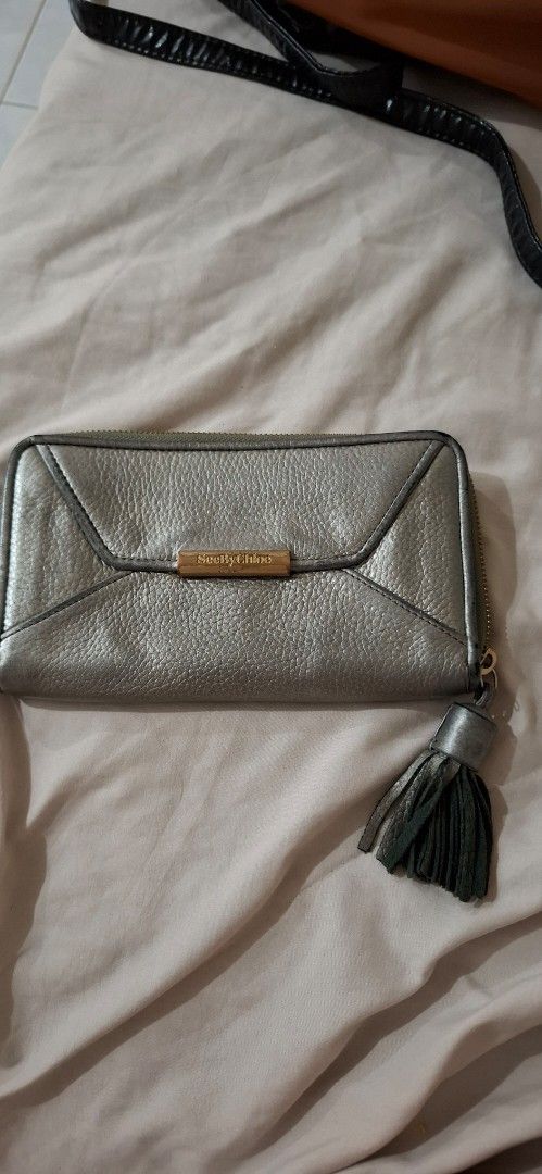 See By Chloe Metallic Silver Zip Around Wallet (Category: Wallets & Card holders) located in Paranaque City. Submitted by finders_thriftersph (Listing ID 1467736954, Image 1). Description: Metallic silver textured leather wallet from See By Chloe. Wrap-around zipper closure with a matching leather tassel pull attached. Gold tone hardware details and embossed branding on the front plate and interior. Fabric lined compartments inside with multiple 