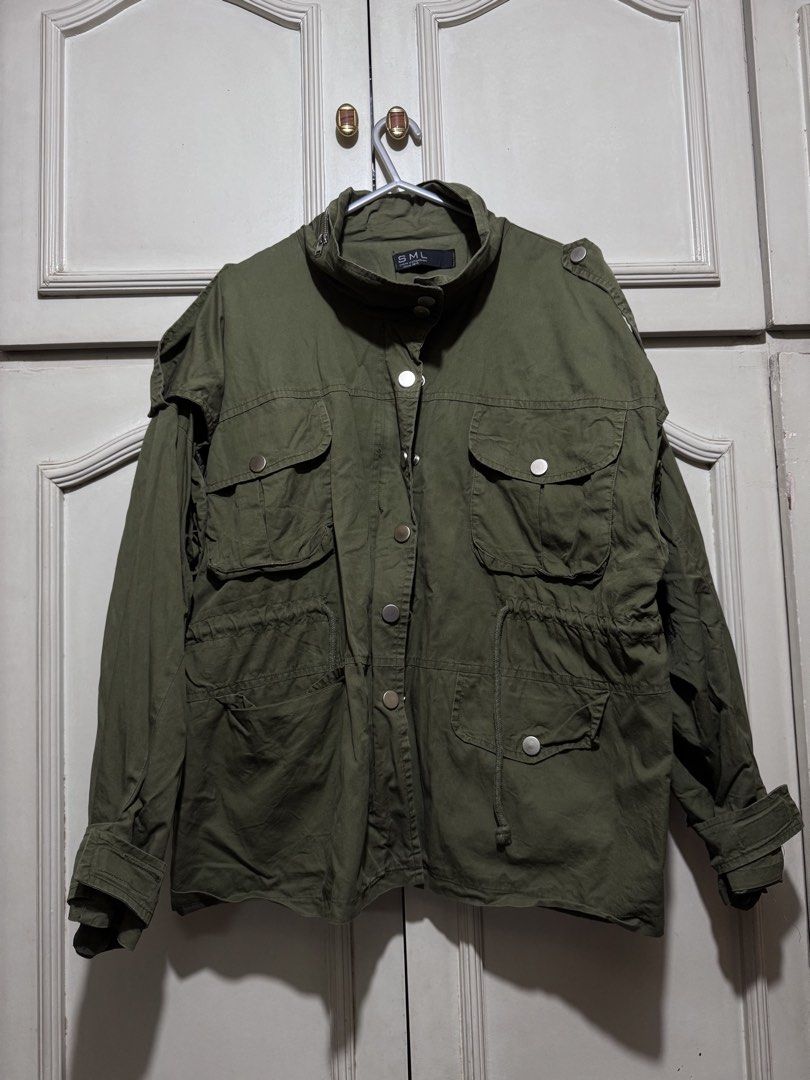 SML Green Utility Jacket Cargo Utility Outerwear (Category: Coats, Jackets and Outerwear) located in Marikina City. Submitted by switkimchi (Listing ID 1467629461, Image 1). Description: - Brand: SML - Color: Army green - Closure: Button-up front with metallic snaps - Pockets: Multiple cargo pockets on chest and lower front - Fit: Adjustable drawstring waist - Collar: High collar for wind protection - Ideal for: Layering, travel, and cooler weath