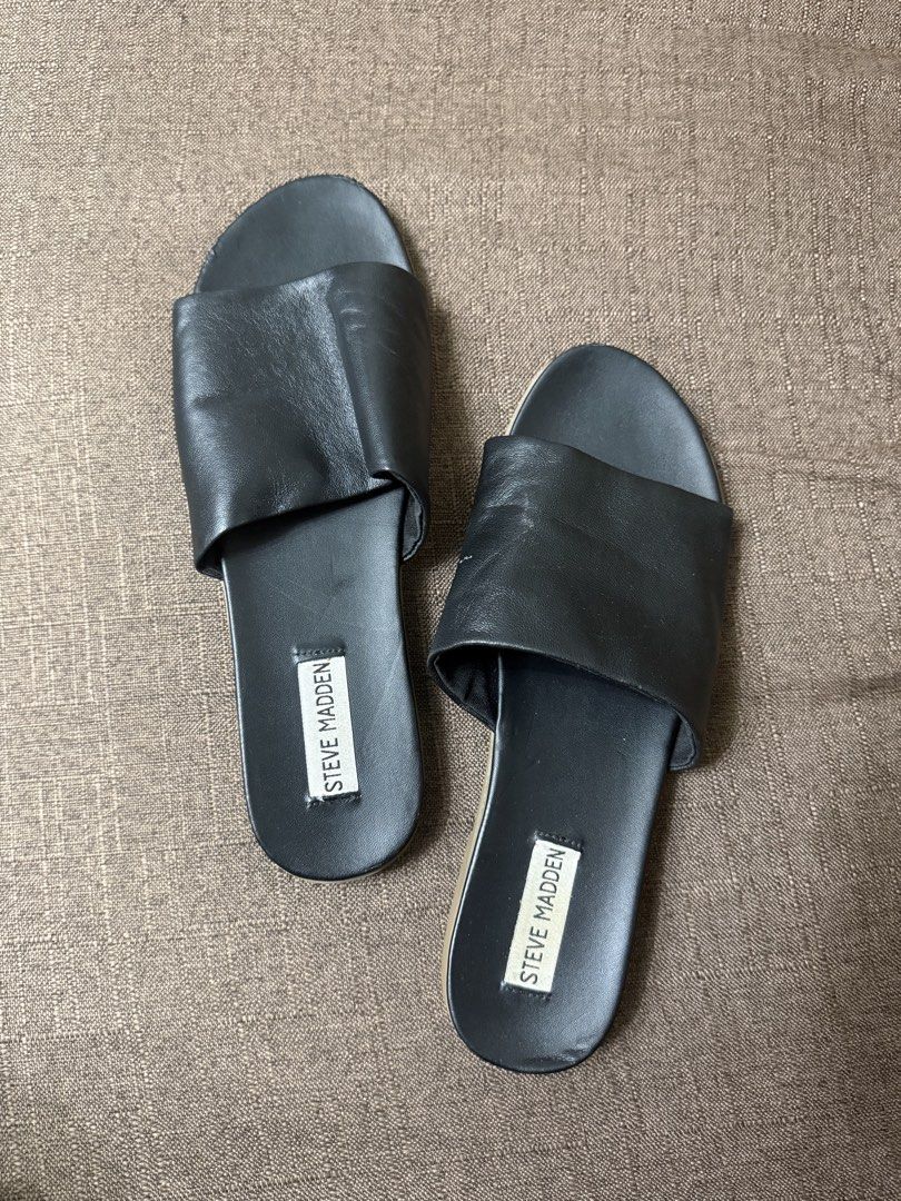 Steve Madden Black Slide Sandals (Category: Flats & Sandals) located in Cainta. Submitted by amswardrobe (Listing ID 1467837857, Image 1). Description: - Brand: Steve Madden - Color: Classic Black - Style: Slip-on slide sandals with wide foot strap and branded insole - Condition: Pre-loved with light wear around the toe edges - Features: Comfortable flat sole, ideal for daily casual wear.