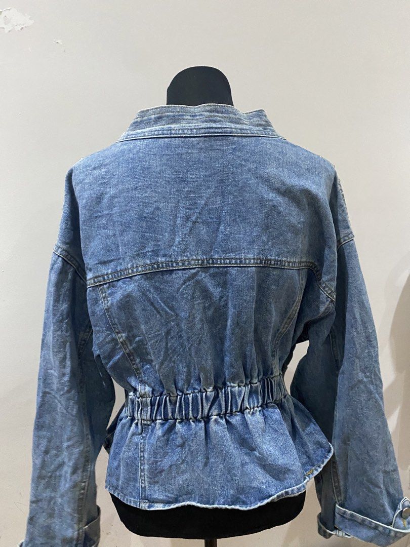 Studded Denim Jacket Peplum Waist V-Neck (Category: Coats, Jackets and Outerwear) located in Manila. Submitted by mpt99876 (Listing ID 1467796270, Image 3). Description: - Style: Statement medium wash denim jacket with silver metal hardware - Neckline: Deep V-neck with two front button closures - Fit: Cinched elastic waist with a stylish peplum flare - Pockets: Two chest pockets with button flaps - Details: Long sleeves with button cuffs and heav