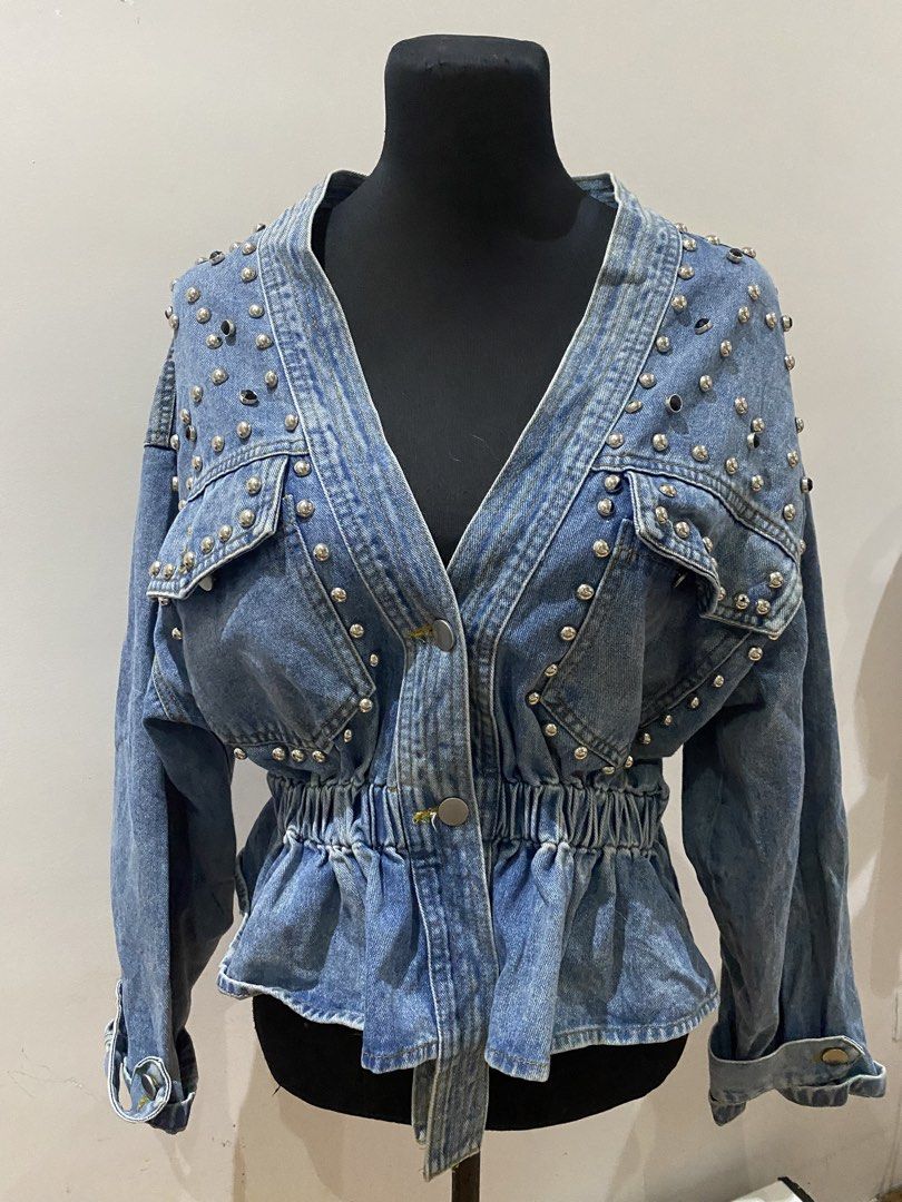 Studded Denim Jacket Peplum Waist V-Neck (Category: Coats, Jackets and Outerwear) located in Manila. Submitted by mpt99876 (Listing ID 1467796270, Image 1). Description: - Style: Statement medium wash denim jacket with silver metal hardware - Neckline: Deep V-neck with two front button closures - Fit: Cinched elastic waist with a stylish peplum flare - Pockets: Two chest pockets with button flaps - Details: Long sleeves with button cuffs and heav