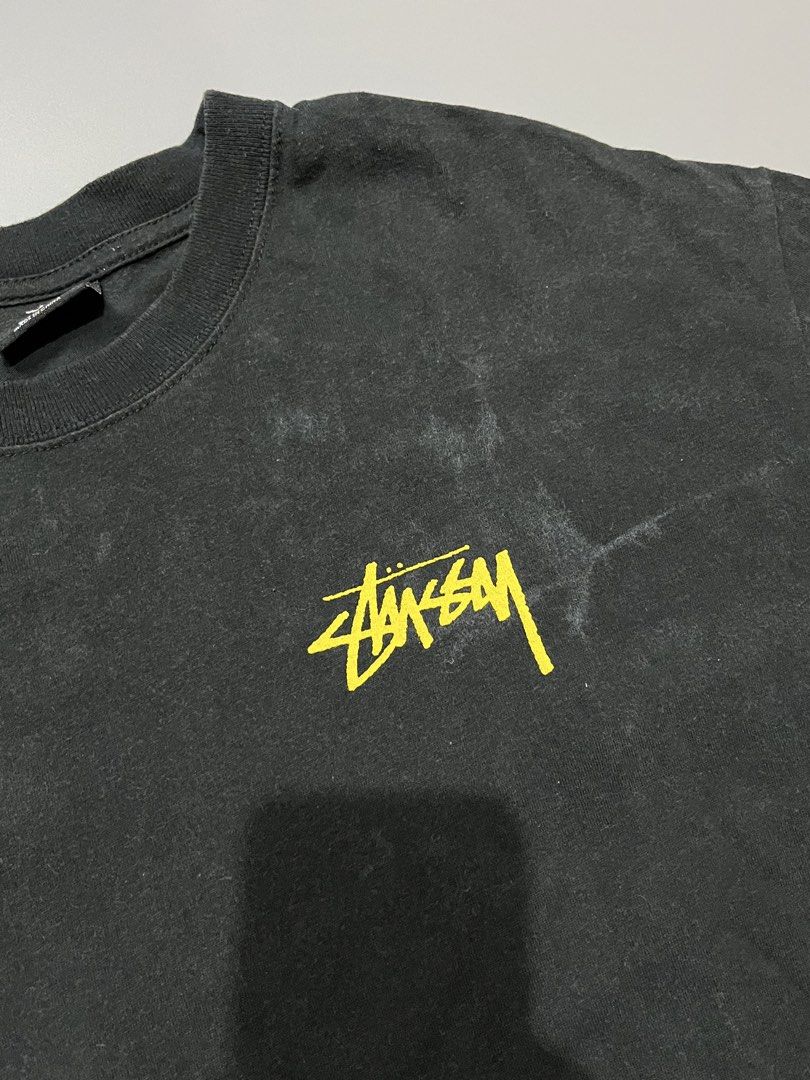 Stussy Graphic Tee Black Size S (Category: Tshirts & Polo Shirts ) located in Manila. Submitted by jorgemabelin2001 (Listing ID 1467760209, Image 2). Description: - Brand: Stussy (Australia tag, Made in China) - Color: Black with yellow logo accents - Size: Small - Material: 100% Cotton - Design: Small chest logo on front, large vintage statue graphic with typography on the back - Fit: Standard crew neckline and short sleeves - Condition: Excelle