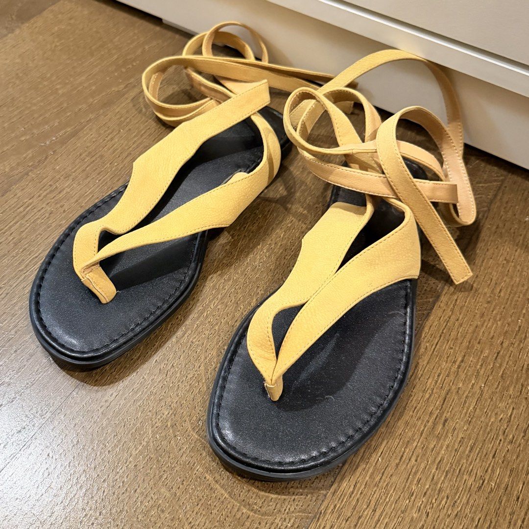 Suede Lace-Up Flat Sandals in Size 8 (Category: Flats & Sandals) located in Makati City. Submitted by agl.ph (Listing ID 1467741607, Image 3). Description: - Color: Beige with contrasting black soles - Style: Thong-style front strap with lace-up ankle design - Size: US8 (stamped on the bottom) - Condition: Brand new, never worn out - Special Feature: Protective plastic film still attached to the soles - Purchased on Amazon for $50.