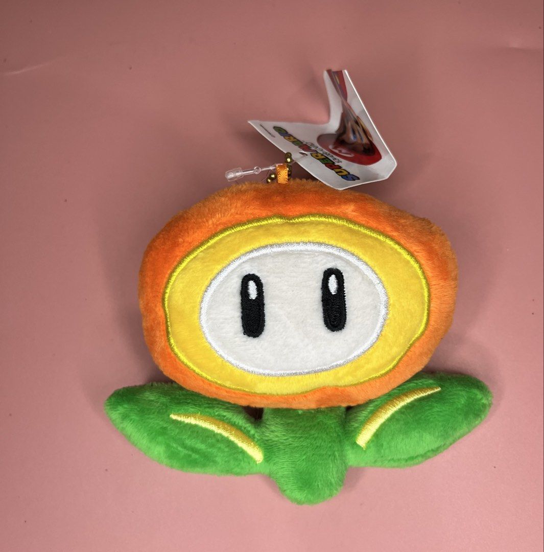 Super Mario Fire Flower Plush Coin Purse (Category: Purses & Pouches) located in Caloocan City. Submitted by snapshop_ph (Listing ID 1467645078, Image 1). Description: - Authentic Super Mario Fire Flower plush coin purse - Soft orange and yellow material with green leaf details - Secure zipper closure with orange mesh-lined interior - Includes golden ball chain strap and clasp for easy hanging on bags or keys - Comes with original hang tags (Grea