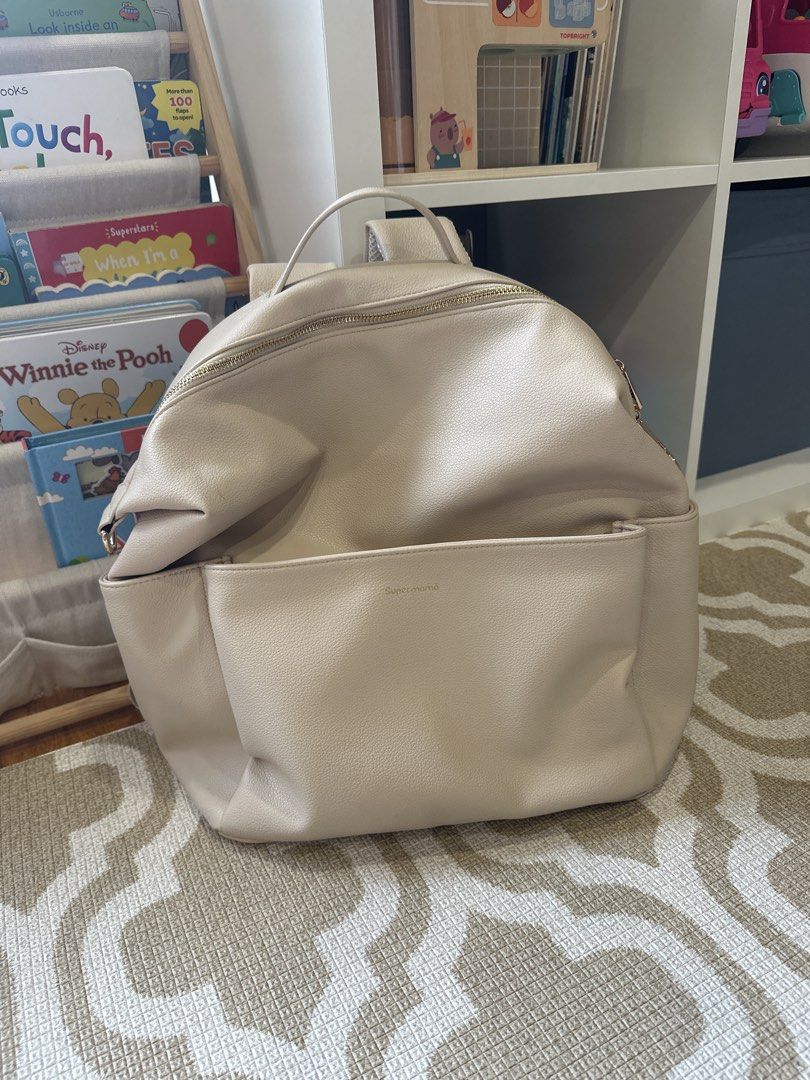 Supermama Beige Diaper Backpack (Category: Diaper Bags & Wetbags) located in Quezon City. Submitted by sherrachan (Listing ID 1467616261, Image 1). Description: - Supermama beige diaper backpack - Elegant gold-tone zippers and front logo stamp - Spacious main compartment with patterned lining, slip pockets, and elasticized storage - Handy front pocket for quick-access items - Comfortable adjustable shoulder straps and top grab handle - Perfect, p