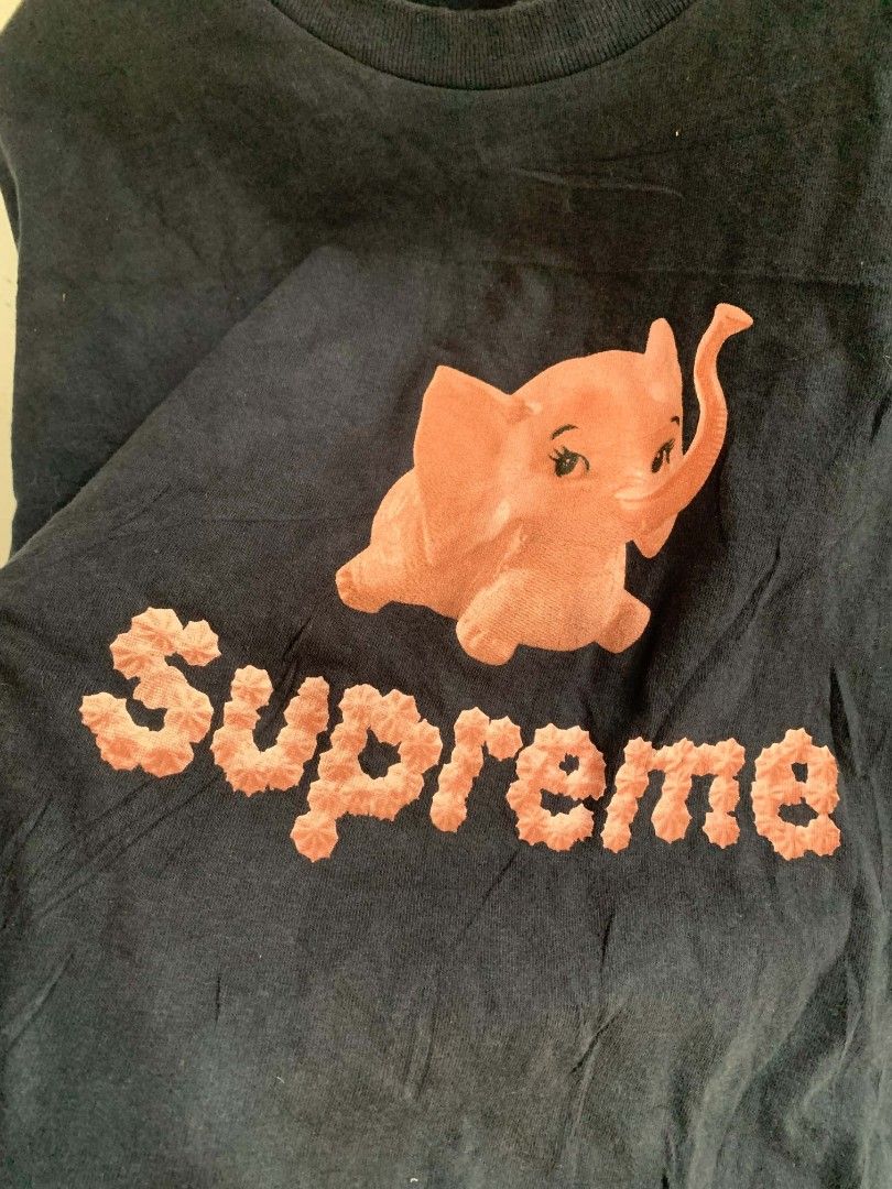 Supreme Elephant Graphic T-Shirt (Category: Tshirts & Polo Shirts ) located in Manila. Submitted by louiseluch69680 (Listing ID 1467647893, Image 2). Description: - Brand: Supreme - Color: Black - Size: XL (dimes 23x32) - Design: Pink elephant graphic with textured Supreme lettering on the front - Material: 100% pre-shrunk cotton - Origin: Made in U.S.A. - Features: Classic crew neck and printed neck tag wash instructions - Condition: Excellent, 