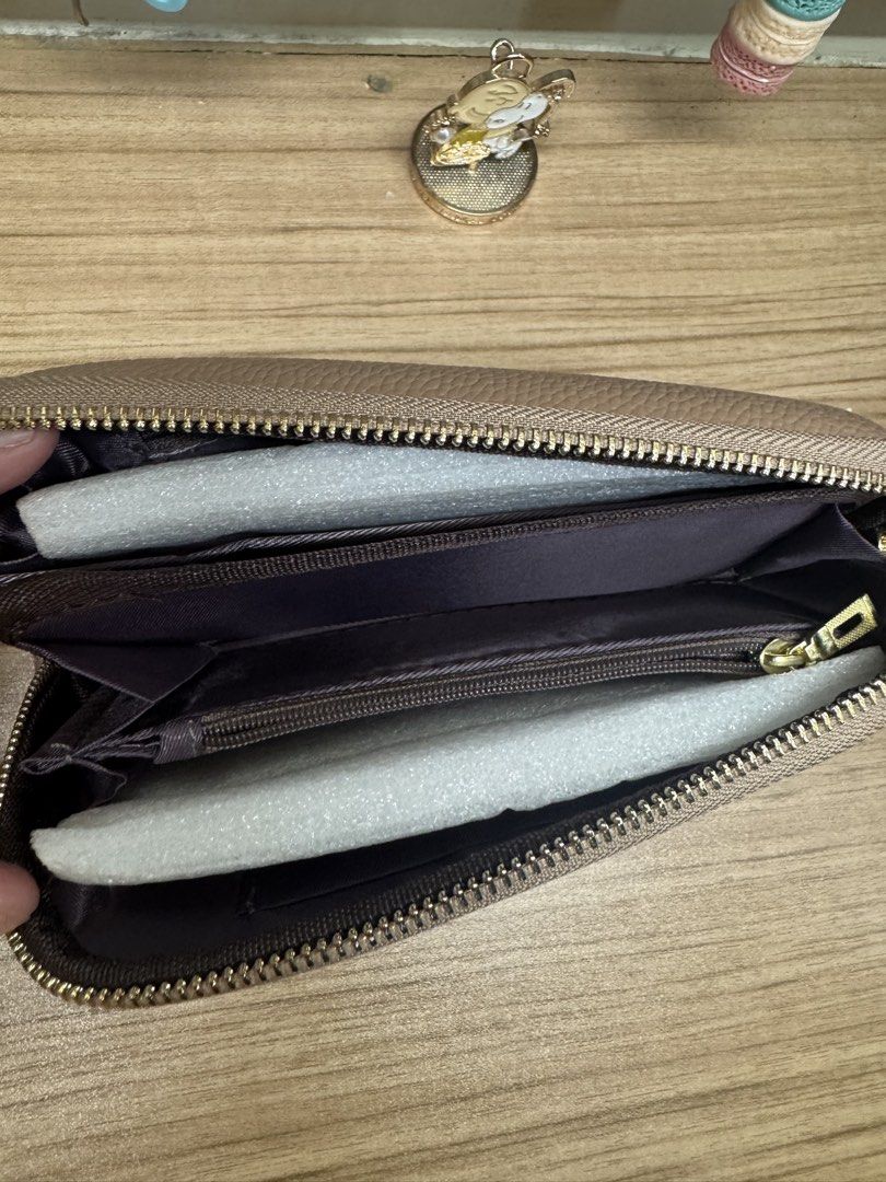 Taupe zip-around long wallet with gold hardware (Category: Wallets & Card holders) located in Manila. Submitted by xenasales (Listing ID 1467648376, Image 2). Description: - Color/Material: Taupe pebbled faux leather with dark brown fabric lining - Hardware: Gold-tone hardware with a distinct front metal clasp detail - Closure: Secure zip-around closure - Compartments: Multiple card slots, bill compartments, and a zippered coin pocket - Condition
