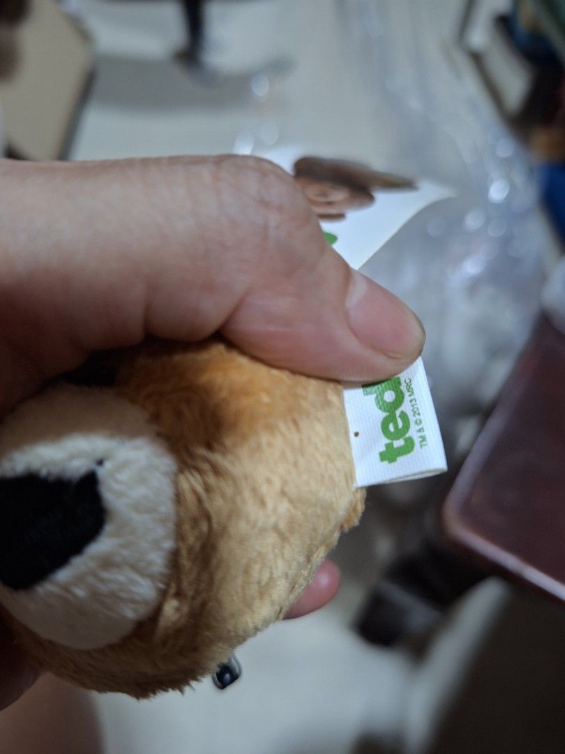 Ted Bear Plush Toy Keychain with Suction Cup (Category: Plushies & Soft Toys) located in Bulacan. Submitted by ourdailyfinds (Listing ID 1467736782, Image 3). Description: - Official Ted movie plush bear head - Comes with original cardboard tag and holographic sticker - Includes a hanging strap and suction cup on the back for easy display - White side tag reads TM and 2013 MRC - Made with soft brown fabric, white muzzle, and black mouth.