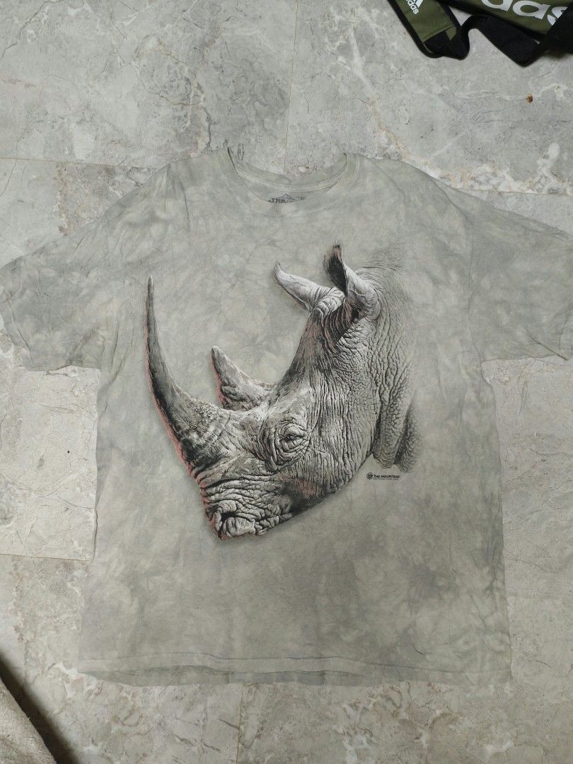 The Mountain Rhino Graphic Tee Size XL (Category: Tshirts & Polo Shirts ) located in Caloocan City. Submitted by delatorreg27719 (Listing ID 1467792048, Image 1). Description: - Brand: The Mountain - Design: Rhinoceros art print by Dimitar Neshev (Dated 2017) - Colorway: Tie-dye grey - Size: XL (Standard fit) - Material: 100% Cotton - Origin: Printed in USA, manufactured in Mexico - Condition: Normal wear consistent with regular use - Features: C