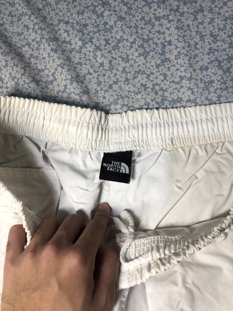 The North Face White Side Striped 3/4s (Category: Joggers) located in Caloocan City. Submitted by castroemman0201 (Listing ID 1467675308, Image 3). Description: - Brand: The North Face - Size: Tagged 105 - Color: White - Fit: Elastic waistband with adjustable drawstring hem at the bottom - Details: Bold mesh side panels with The North Face branding and embroidered logo near the front pocket - Pockets: Convenient zip pocket on the side with a bran