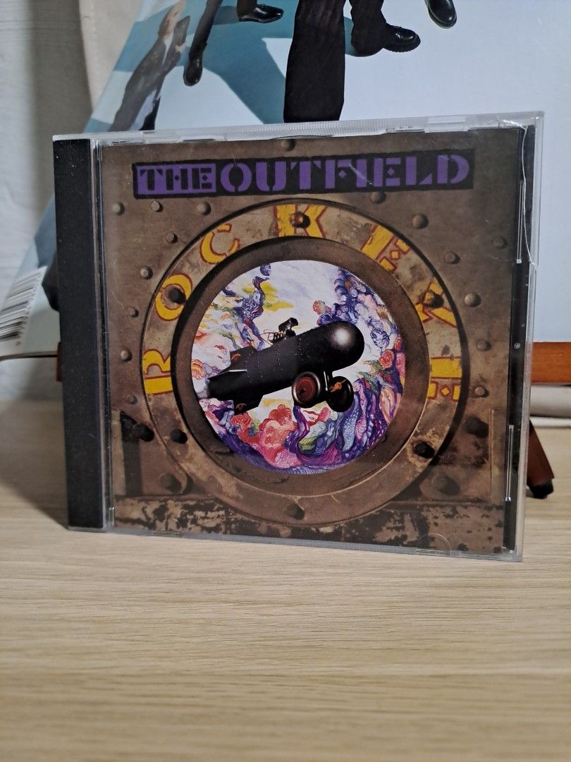 The Outfield CD Album (Category: CDs & DVDs) located in Las Pinas. Submitted by cobieshop (Listing ID 1467759494, Image 1). Description: - Artist/Album: The Outfield music album on compact disc - Packaging: Standard jewel case with minor exterior surface wear - Artwork: Submarine graphic inside a metal porthole design with purple spine typography - Condition: Great addition to any rock music CD collection.