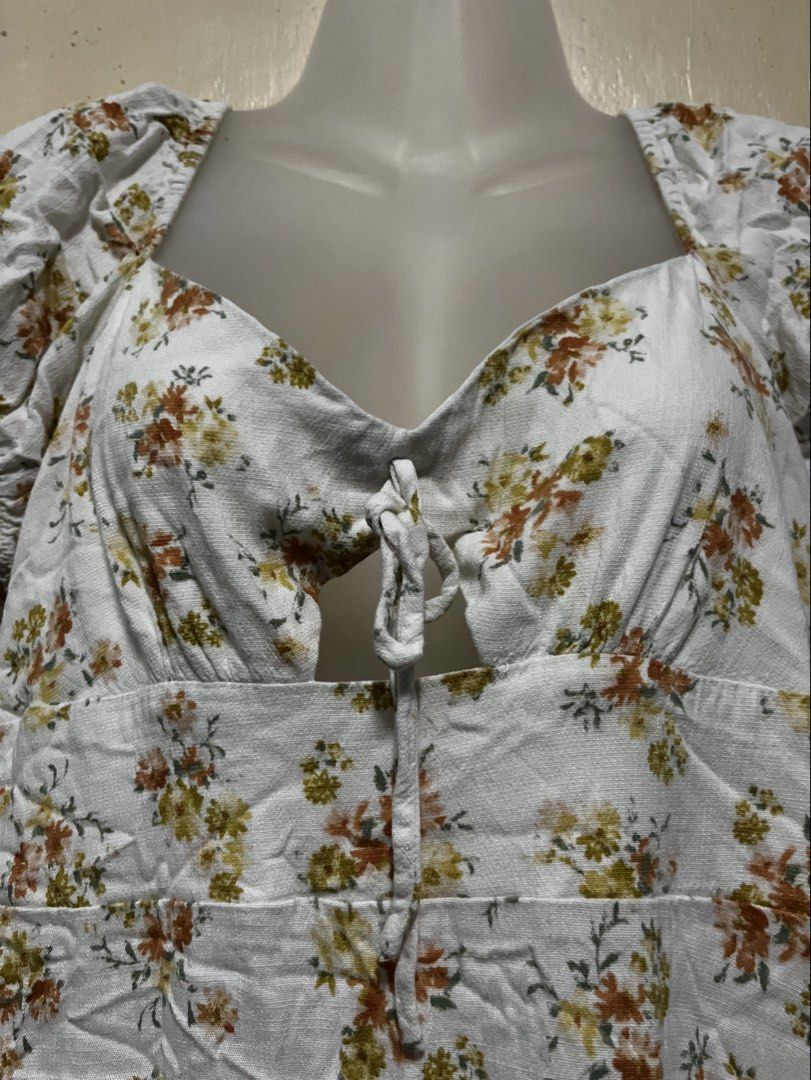 Floral Print Ruffle Dress (Category: Dresses) located in Tabuk. Submitted by zenwolf-1867 (Listing ID 1467774234, Image 3). Description: - Style: White mini dress with all-over orange and yellow floral print - Neckline: Sweetheart neckline with front tie keyhole cutout - Details: Trendy puff sleeves and layered ruffle hem - Sizing: Tagged size 11 - Origin: Made in China.