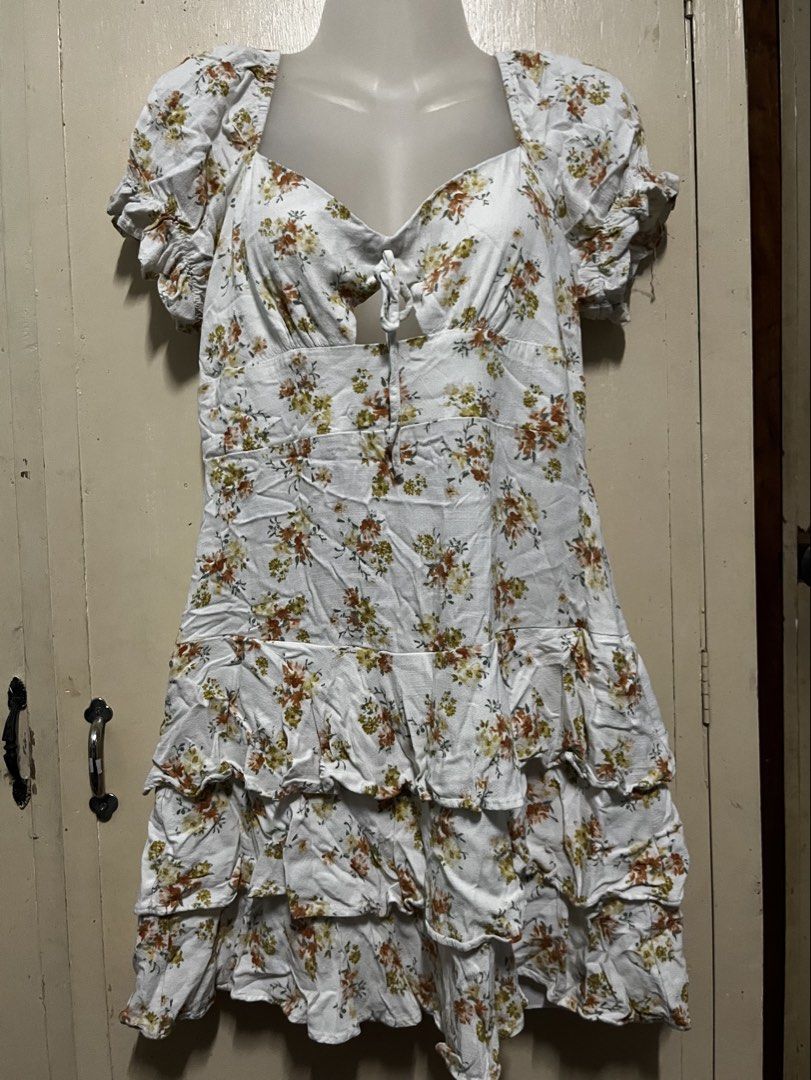 Floral Print Ruffle Dress (Category: Dresses) located in Tabuk. Submitted by zenwolf-1867 (Listing ID 1467774234, Image 2). Description: - Style: White mini dress with all-over orange and yellow floral print - Neckline: Sweetheart neckline with front tie keyhole cutout - Details: Trendy puff sleeves and layered ruffle hem - Sizing: Tagged size 11 - Origin: Made in China.