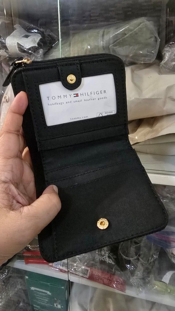 Tommy Hilfiger Monogram Small Black Wallet (Category: Wallets & Card holders) located in Quezon City. Submitted by momof3_11 (Listing ID 1467755514, Image 3). Description: - Brand: Tommy Hilfiger - Color: Classic Black with All-Over Monogram Pattern - Condition: Brand new with tags attached - Closure: Secure snap button closure - Interior: Multiple card slots and a clear ID window - Compartments: Dedicated zippered coin pocket and cash sleeve - D