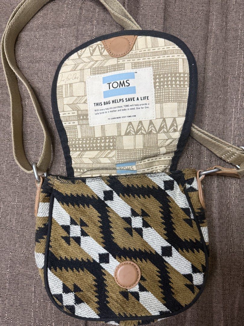 TOMS Aztec Print Crossbody Bag (Category: Cross-body Bags) located in Cainta. Submitted by amswardrobe (Listing ID 1467836630, Image 3). Description: - Brand: TOMS - Style: Crossbody bag with Aztec print in beige, black, and white - Closure: Magnetic snap - Strap: Adjustable for custom comfort - Interior: Includes a handy zippered pocket and the iconic 'This bag helps save a life' patch - Material: Durable canvas and textured fabric exterior with
