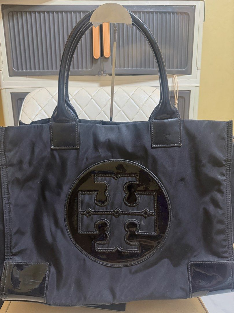 Tory Burch Black Nylon Tote Bag (Category: Tote Bags) located in Tarlac. Submitted by kayeshe (Listing ID 1467740073, Image 2). Description: - 100% authentic - Material: Durable black nylon with patent leather trim and handles - Features: Large patent leather front logo, magnetic top snap closure - Interior: Beige fabric lining with a zippered pocket and metal logo plaque - Condition: Roomy everyday bag with minor wear on patent trim corners.