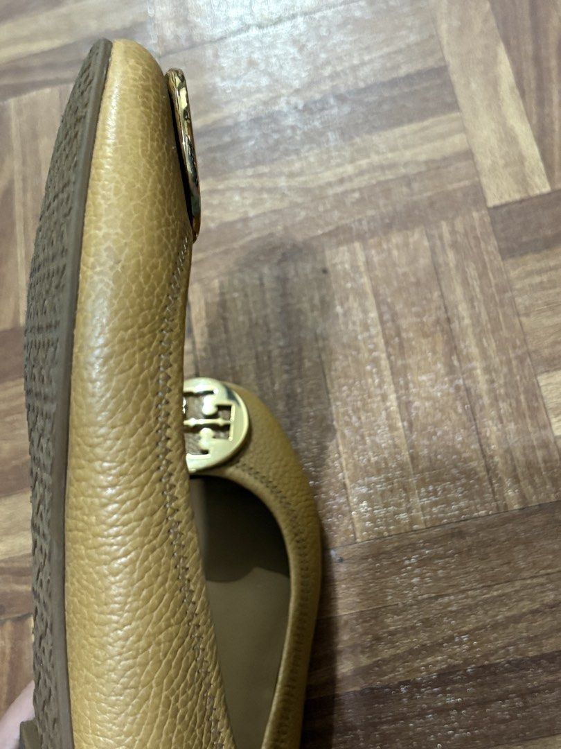 Tory Burch Gold Leather Ballet Flats (Category: Flats & Sandals) located in Manila. Submitted by nykji96 (Listing ID 1467830724, Image 3). Description: - Brand: Tory Burch - Style: Slip-on ballet flats with round toe - Color/Material: Gold textured leather with tan leather lining - Details: Large polished gold logo plaque on vamp - Soles: Textured rubber soles - Condition: Comfort wear with minor signs of handling and slight heel wear - Perfect f