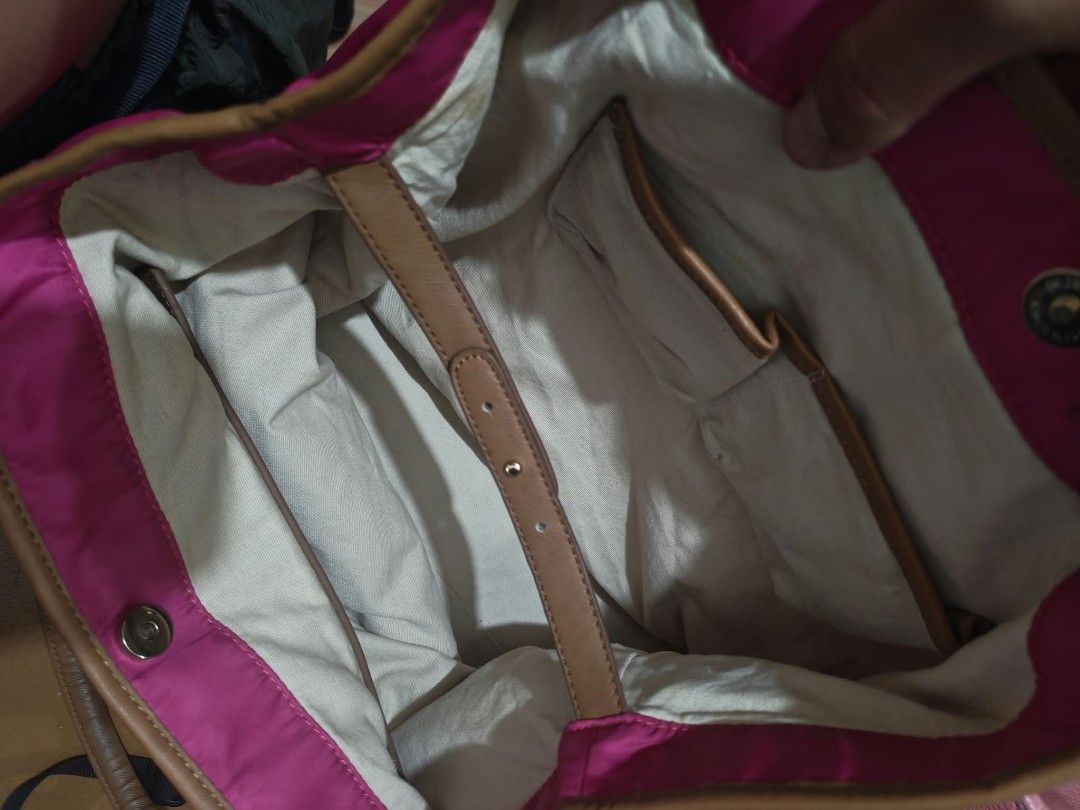 Tory Burch Pink Nylon Tote Bag (Category: Tote Bags) located in Baguio. Submitted by solo_ukay (Listing ID 1467787464, Image 3). Description: - Brand: Tory Burch - Material: Durable bright pink nylon with tan leather handles - Design: Large circular logo patch on the front - Interior: Cream fabric lining with compartments and a zipped pocket - Closure: Secure top magnetic closure - Condition: Clean, protective plastic still on the interior zipper