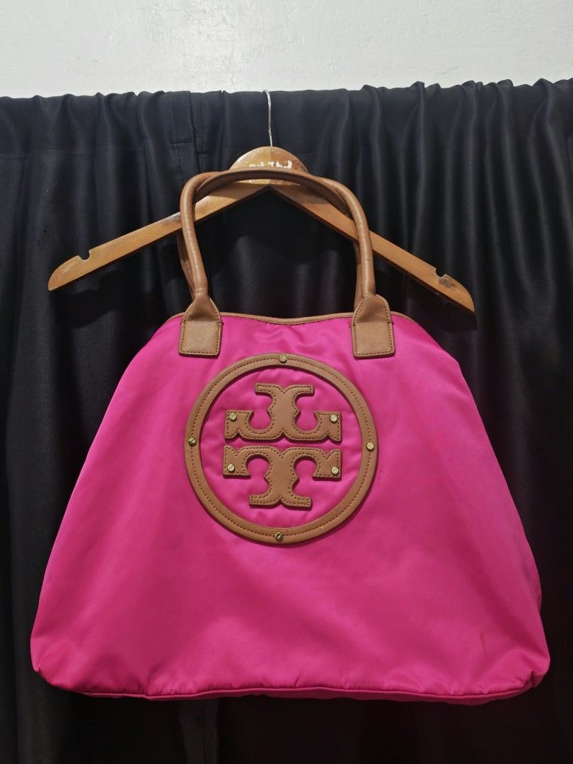 Tory Burch Pink Nylon Tote Bag (Category: Tote Bags) located in Baguio. Submitted by solo_ukay (Listing ID 1467787464, Image 1). Description: - Brand: Tory Burch - Material: Durable bright pink nylon with tan leather handles - Design: Large circular logo patch on the front - Interior: Cream fabric lining with compartments and a zipped pocket - Closure: Secure top magnetic closure - Condition: Clean, protective plastic still on the interior zipper