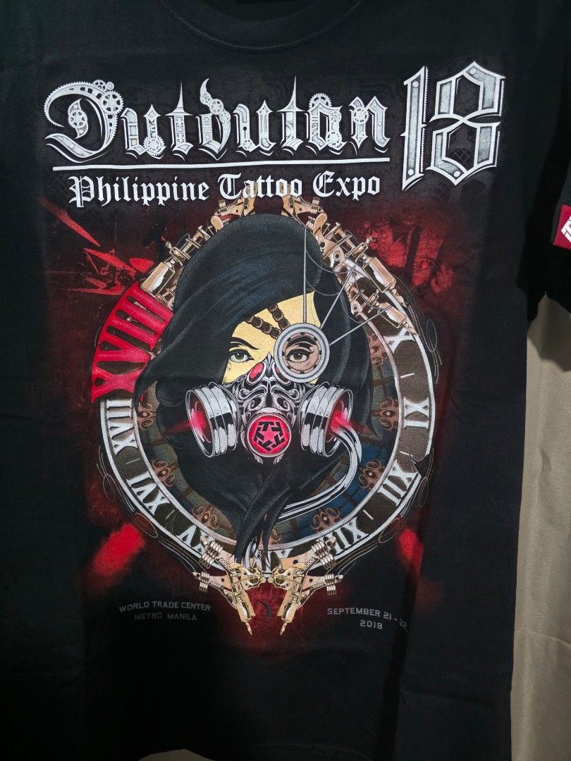 Tribal Dutdutan 18 Large (Category: Tshirts & Polo Shirts ) located in Santa Rosa. Submitted by rowhell09 (Listing ID 1467775315, Image 3). Description: Tribal Dutdutan 18 Large Like new MOD. LBC MOP. BDO, GCASH LOC. NUEVA ECIJA Meet up. Santa rosa Nueva Ecija - Condition: Like new, still sealed in original plastic packaging - Size: Large - Color: Black - Design: Bold front print with a masked figure, tattoo machines, Roman numerals, and gears - 