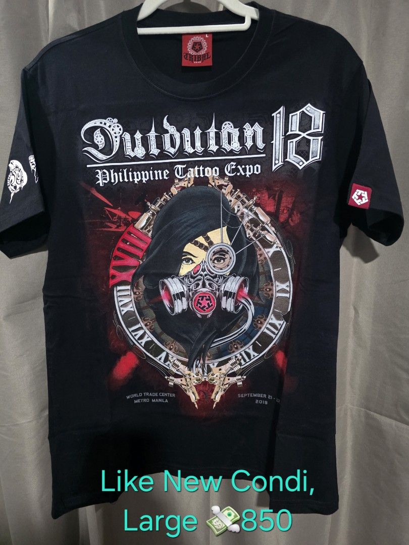 Tribal Dutdutan 18 Large (Category: Tshirts & Polo Shirts ) located in Santa Rosa. Submitted by rowhell09 (Listing ID 1467775315, Image 1). Description: Tribal Dutdutan 18 Large Like new MOD. LBC MOP. BDO, GCASH LOC. NUEVA ECIJA Meet up. Santa rosa Nueva Ecija - Condition: Like new, still sealed in original plastic packaging - Size: Large - Color: Black - Design: Bold front print with a masked figure, tattoo machines, Roman numerals, and gears - 