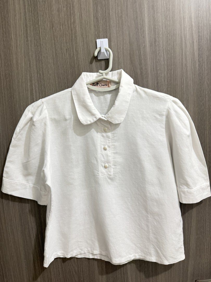Twill Cavern White Peter Pan Collar Blouse (Category: Blouses) located in Manila. Submitted by ktyyycloset (Listing ID 1467742515, Image 3). Description: Peter pan collar with button placket down the front. Short puff sleeves with stitched cuffs. Lightweight fabric with a textured weave. Solid white color throughout. Clean back with a straight hem. -Used once only.