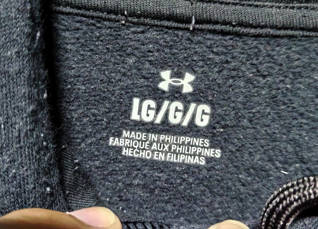 Under Armour Black Hoodie LG (Category: Hoodies) located in Quezon. Submitted by miksxthrift (Listing ID 1467740585, Image 3). Description: - Brand: Under Armour - Color: Black with white embroidered chest logo - Size: Large (Relaxed fit) - Material: Comfortable fleece interior - Features: Front kangaroo pocket, adjustable drawstring hood - Origin: Made in the Philippines - Condition: Ideal for casual days and workouts.
