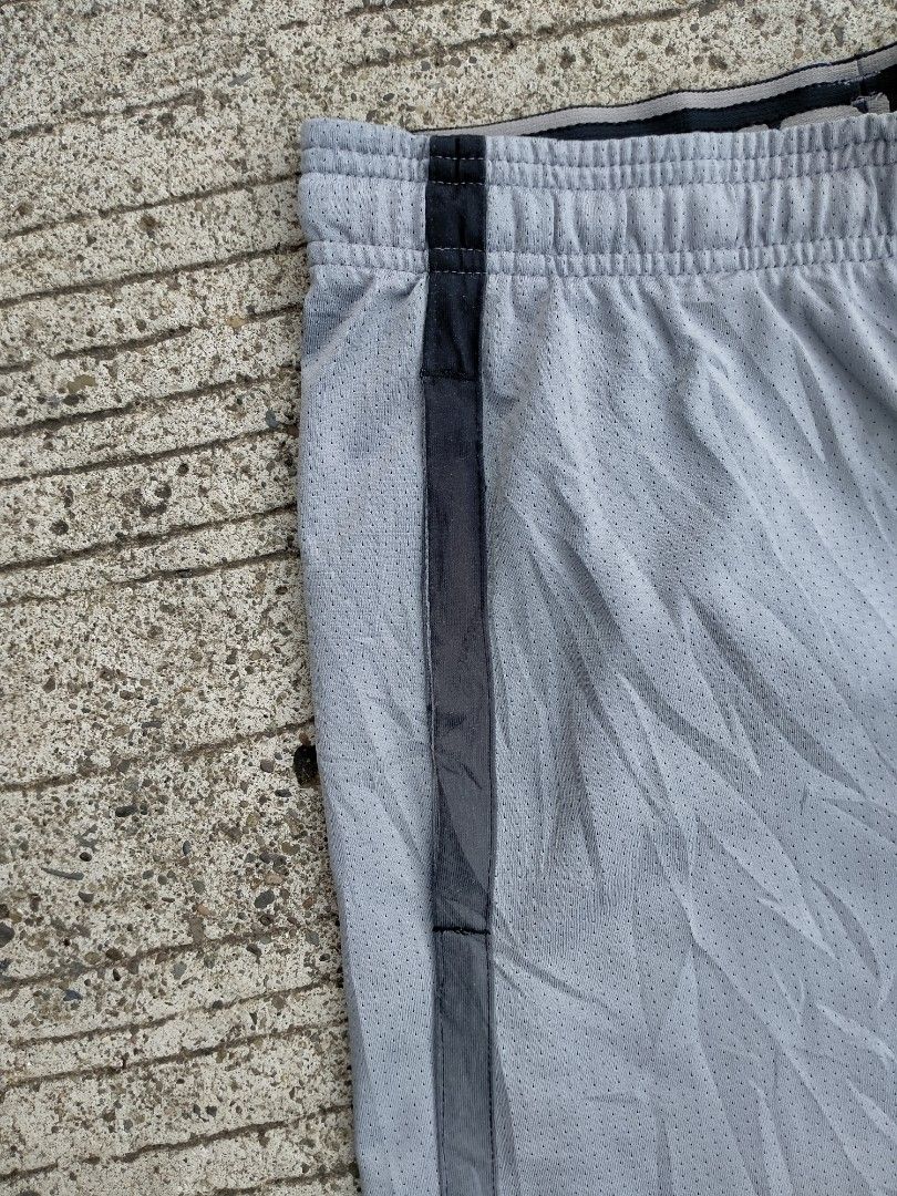 Under Armour Grey Mesh Athletic Shorts Size MD (Category: Shorts) located in Davao. Submitted by ervinpolino09 (Listing ID 1467683734, Image 3). Description: - Brand: Under Armour - Type: Grey mesh athletic shorts - Size: Medium - Fit: Loose fit with elastic waistband and adjustable drawstring - Features: Side pockets and black accent stripes on both legs - Branding: Small black Under Armour logo near bottom hem - Origin: Made in Indonesia.