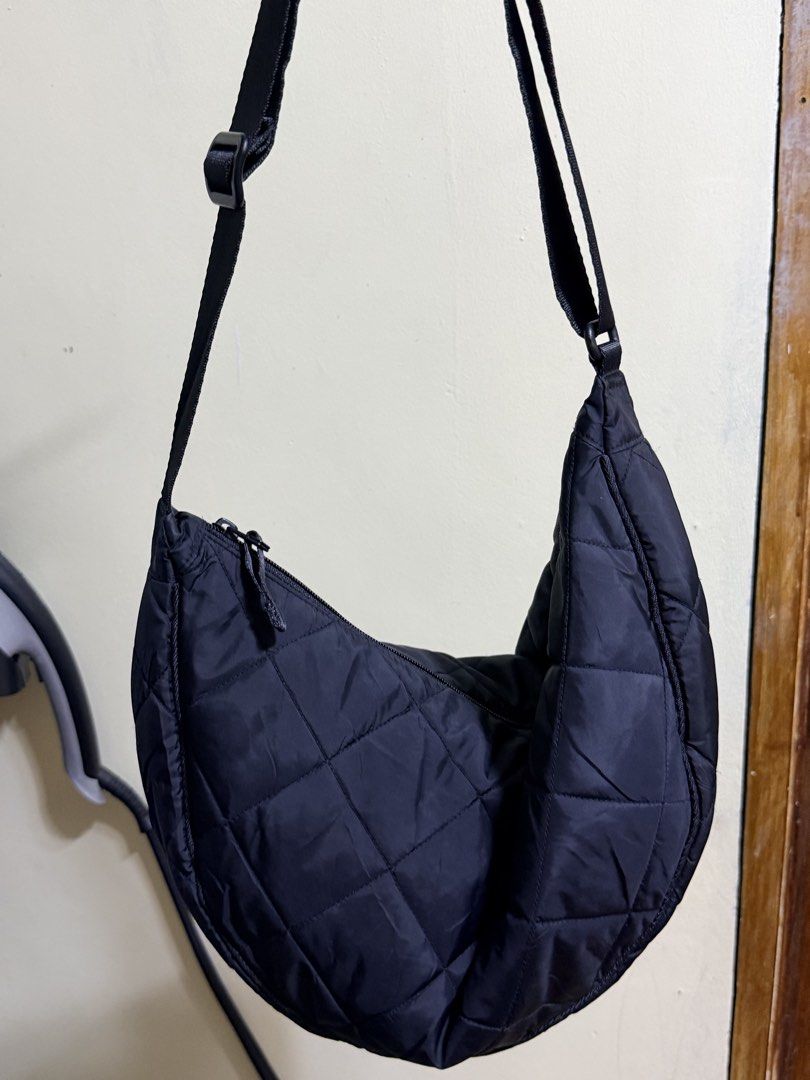 Uniqlo Quilted cresent Shoulder Bag Black (Category: Shoulder Bags) located in Paete. Submitted by skydruemadison (Listing ID 1467719625, Image 2). Description: Black quilted shoulder bag from Uniqlo. Crescent shape with a zipped main compartment and interior pocket. Adjustable strap with buckle. Lightweight nylon material, quilted pattern all over. Spacious inside for daily essentials. Clean interior lining with brand tag attached inside..